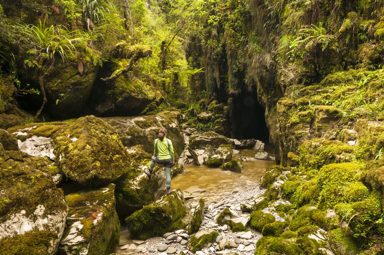 Cave creek with massive, moss covered rocks near Punakaiki and hiker. Photo: Petr Hlavacek