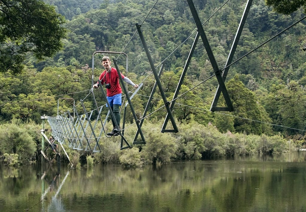 Malcolm tiptoes along the three ­wire bridge over the swollen Seaforth River. Photo: Ray Salisbury