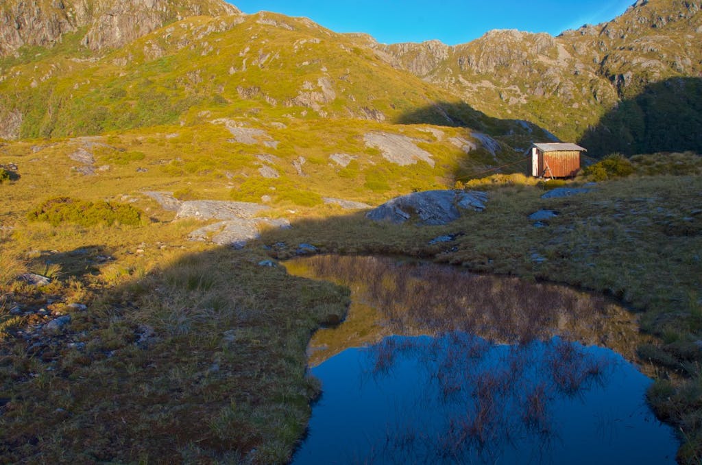 Robin Saddle Hut sits on a bench above the Irene River which flows into Charles Sound. Photo: Carl Walrond