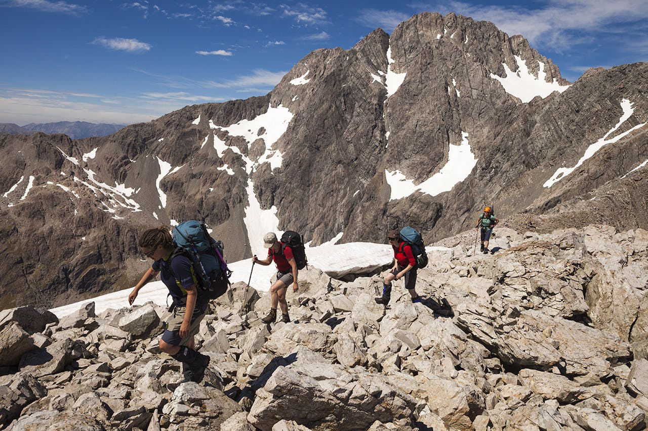Trampers traverse Mt Philistine’s ridge with The Slide and Otira Face of Mt Rolleston creating a dramatic backdrop. Photo: Mark Watson