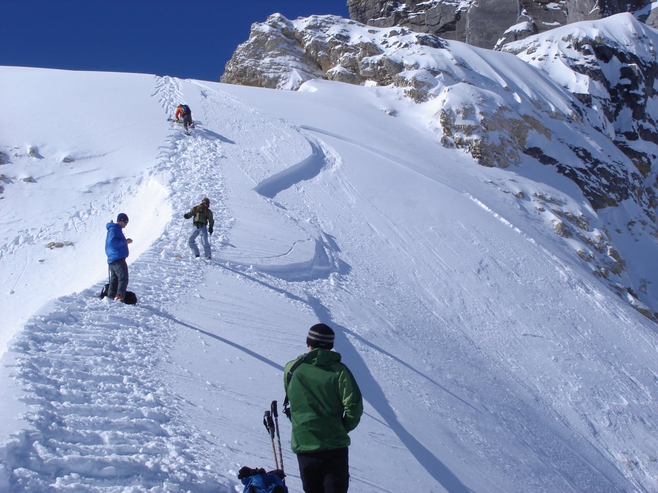 Backcountry skiers climb a safe ridge next to a slope which has just avalanched – if in doubt about the route, speak up