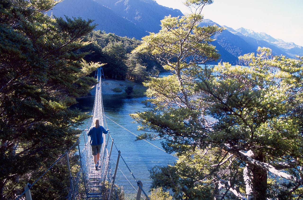 Girl walks on swingbridge across Southern Mavora Lakes, Southland, New Zealand. Photo: www.derekmorrison.co.nz