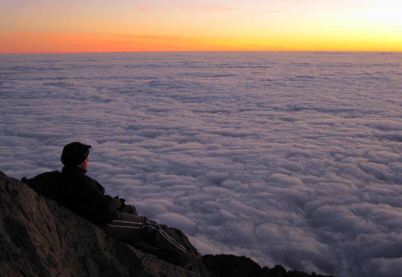 Jamie Bai enjoys a spectacular sunset before bivying the night on Mt Taranaki, in Egmont National Park. Photo: Marcus Bai