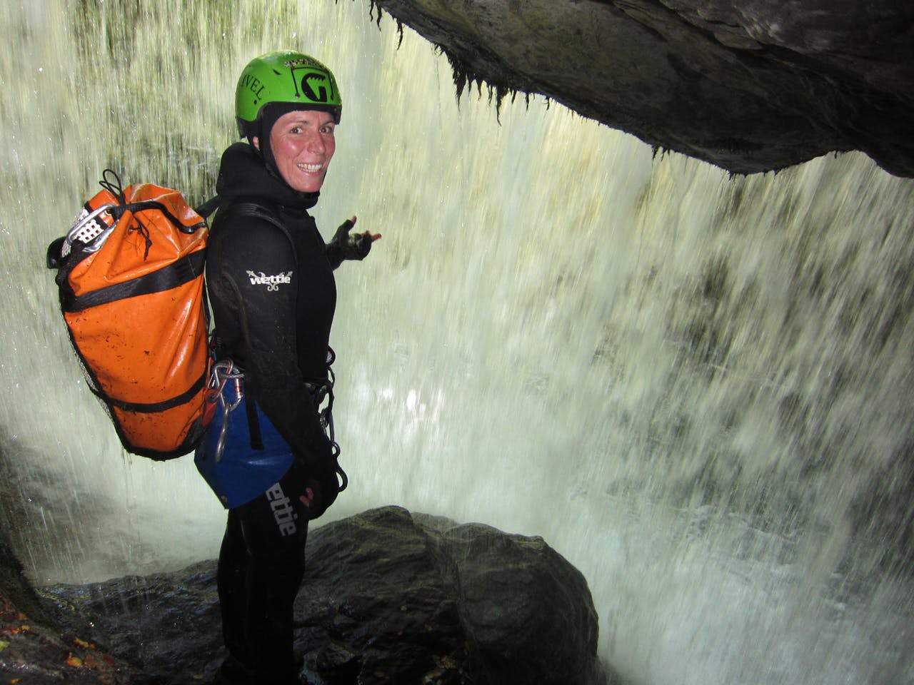 Canyon guide Anna Crafar looks out at the world from behind a waterfall. Photo: Dave Vass