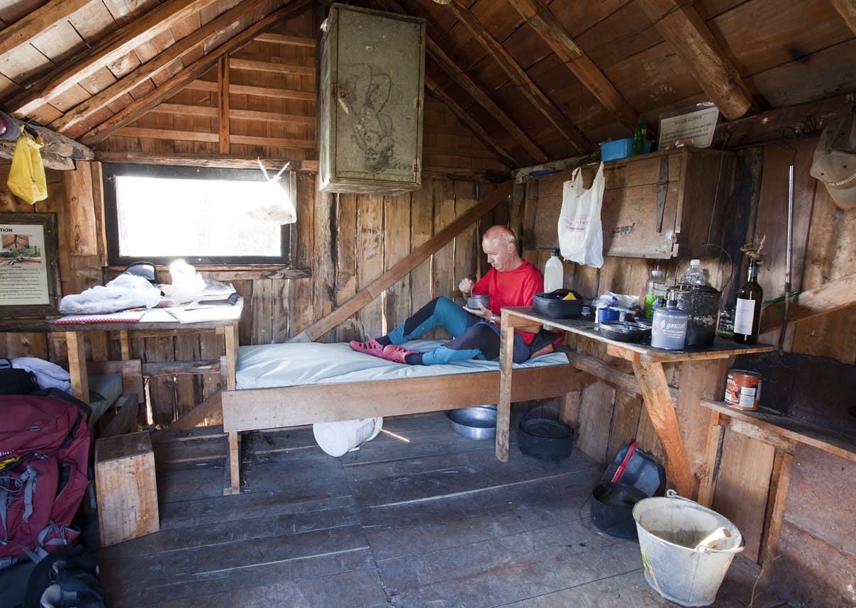 A tramper soaks in the atmosphere of the restored Riordans Hut – the first on the track to get an upgrade. Photo: Ray Salisbury
