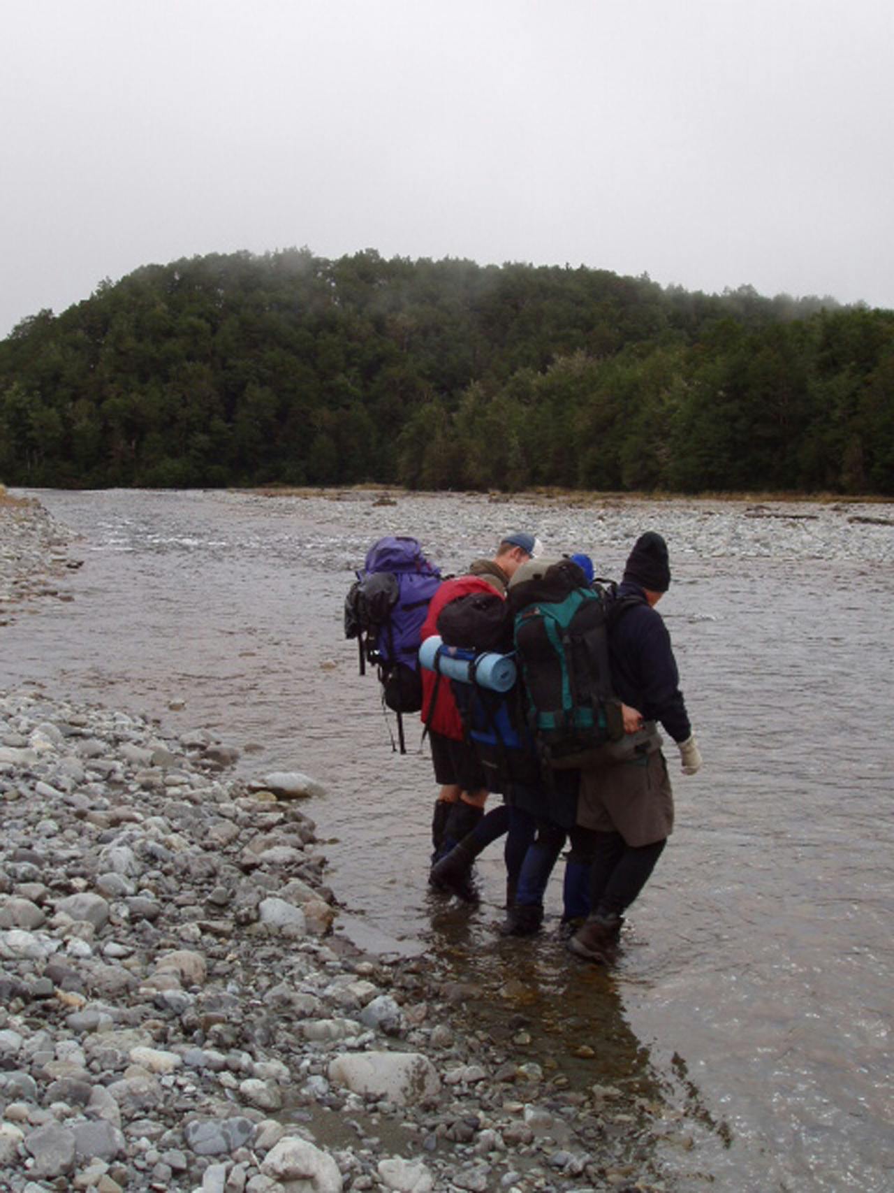 Trampers demonstrate the mutual support method for crossing rivers