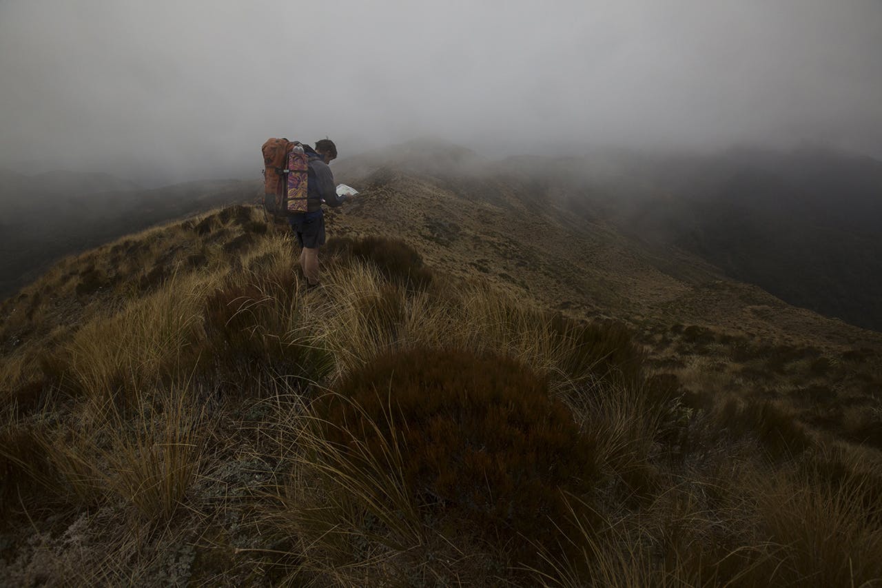 Navigating in low cloud on the tops above the Moonlight Track. One of the concerns voiced about the route is inexperienced hikers will need to travel through long exposed sections with little shelter. Photo: Neil Silverwood